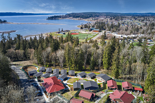 Aerial view of Village of Hope tiny homes with the clear blue bay near by and the islands in the distance.
